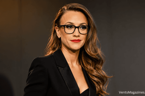 Shani Levni in a sophisticated black blazer and glasses against a clean studio background.