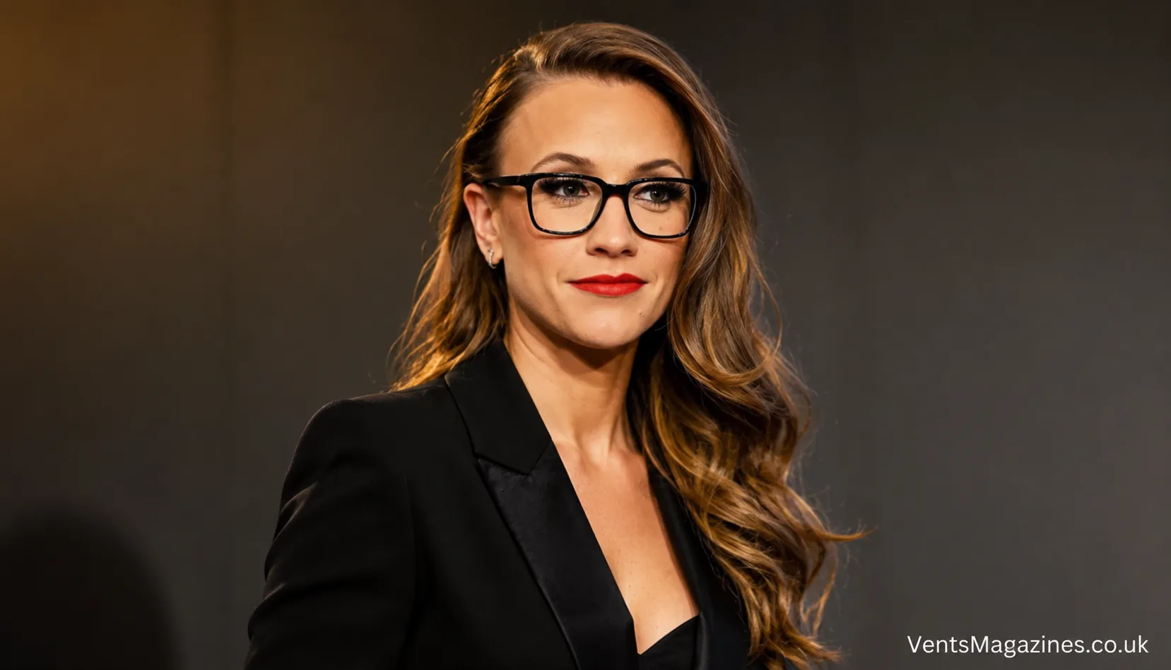 Shani Levni in a sophisticated black blazer and glasses against a clean studio background.