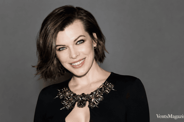 Mila Volovich portrait featuring a confident studio headshot against a clean grey background, styled in elegant black attire with a jeweled neckline.