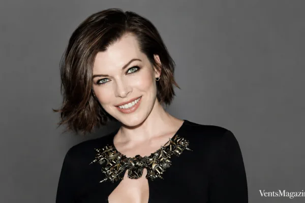 Mila Volovich portrait featuring a confident studio headshot against a clean grey background, styled in elegant black attire with a jeweled neckline.